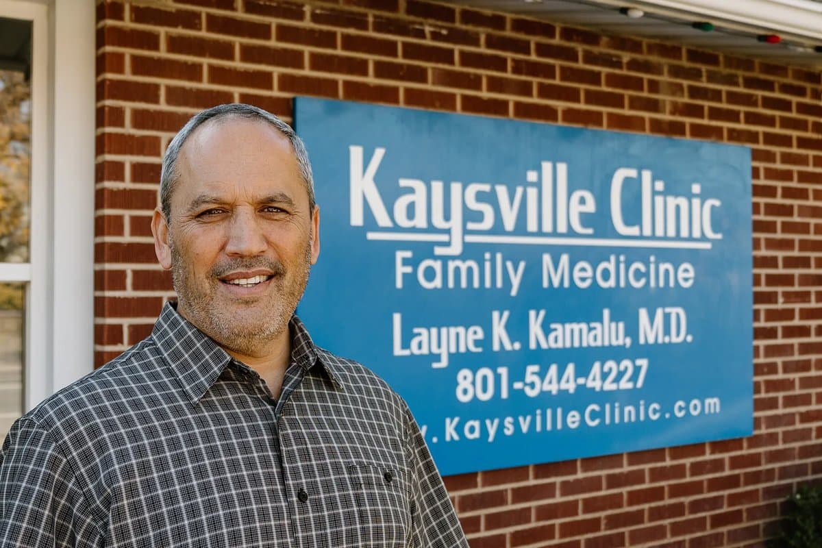 Dr. Layne Kamalu, M.D. standing in front of the Kaysville Clinic sign